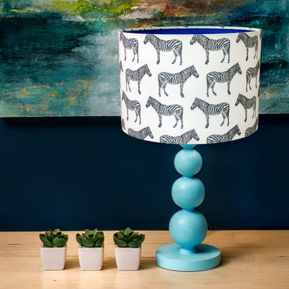 Table lamp with zebra pattern drum shade.